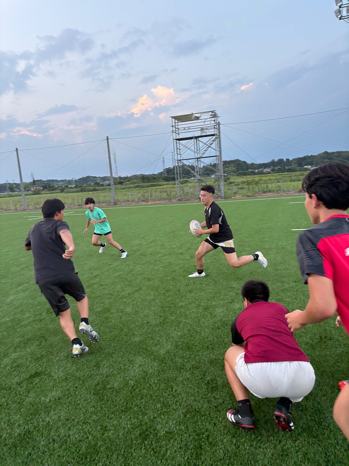 夕暮れのグラウンドでパスを回す選手たち